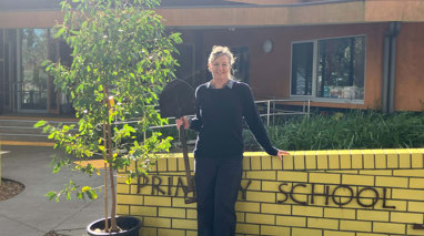 A woman stands with a shovel against a yellow wall