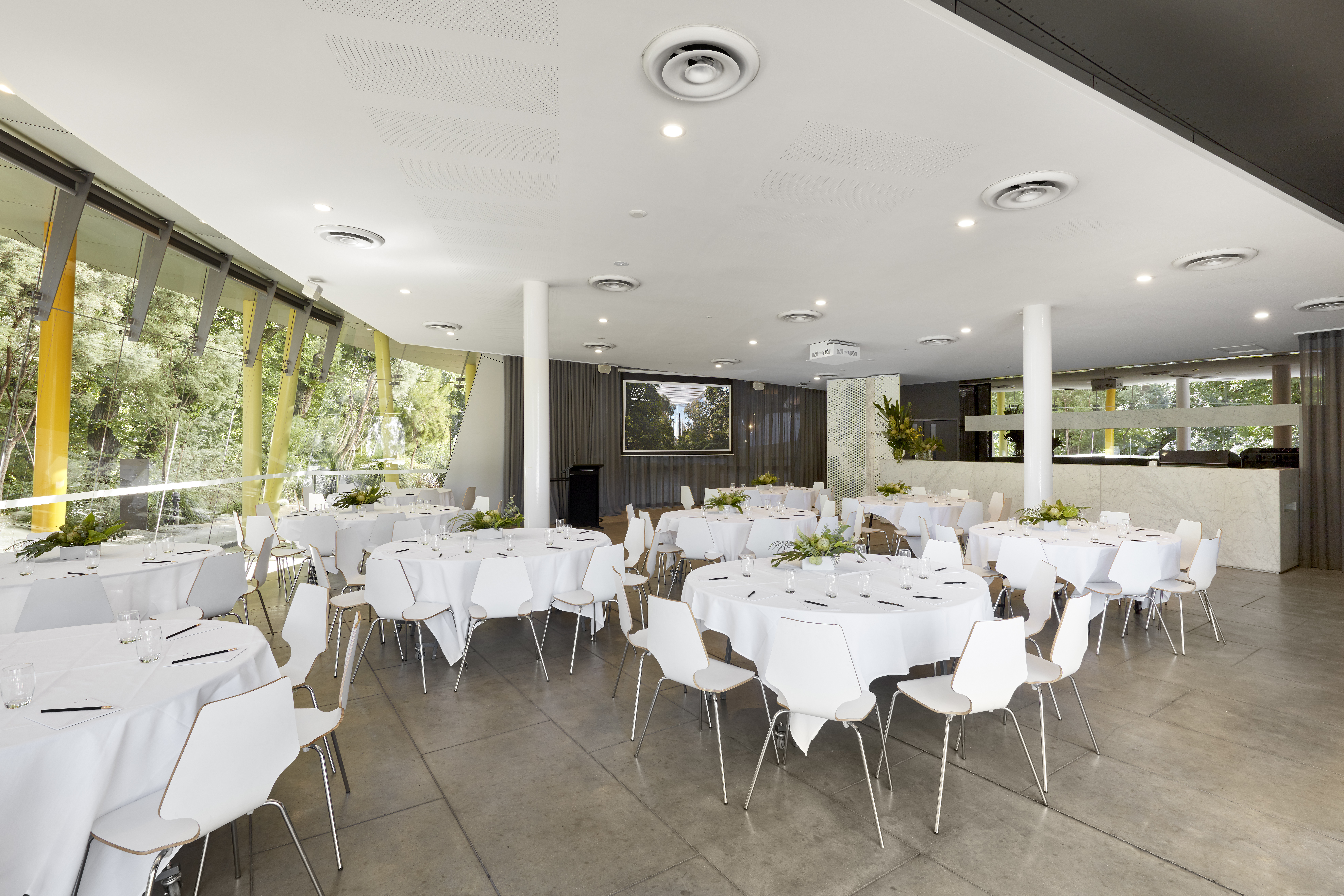 Room set up with round tables and chairs with white tablecloths