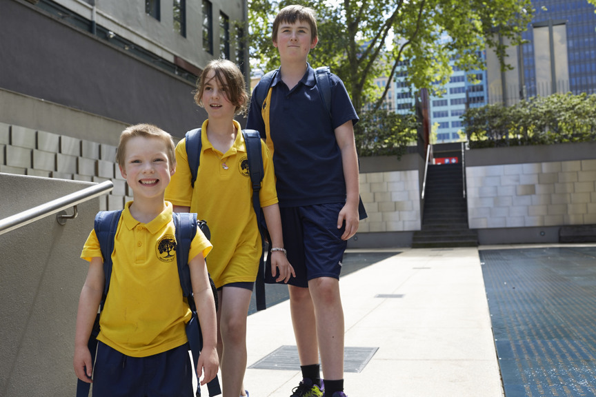 Three children of different ages walking in the Immigration Museum courtyard. 