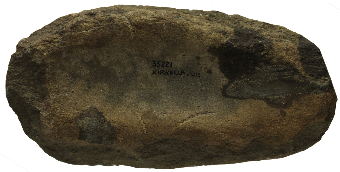 A large stone with a wide and long groove running through it. 