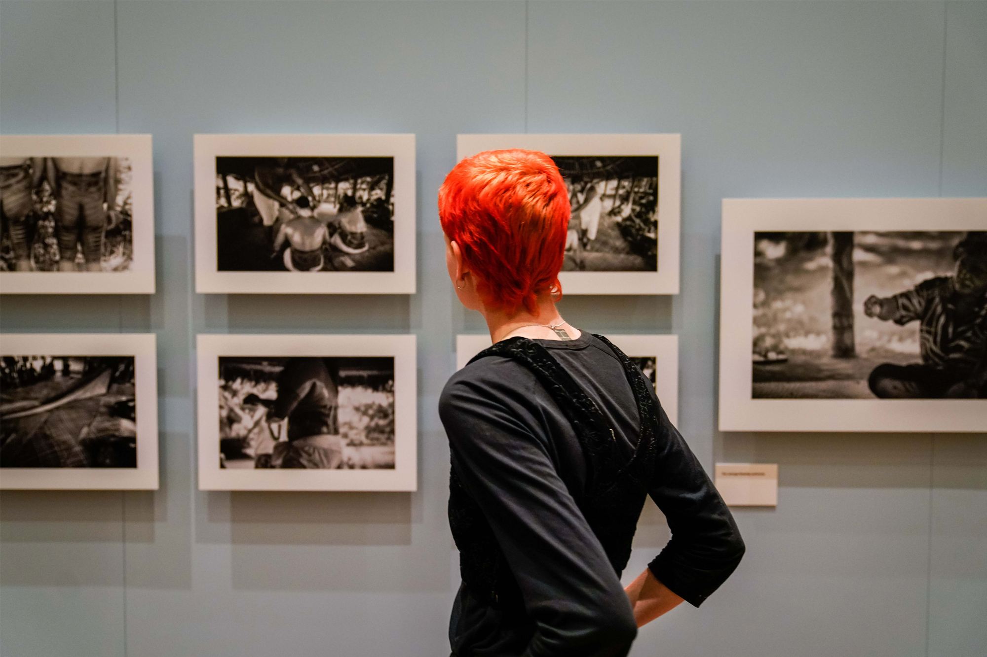 Woman with short cropped red hair looking at black and white photographs