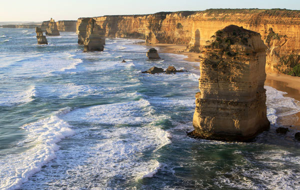 Waves rolling past rock formations in front of cliffs