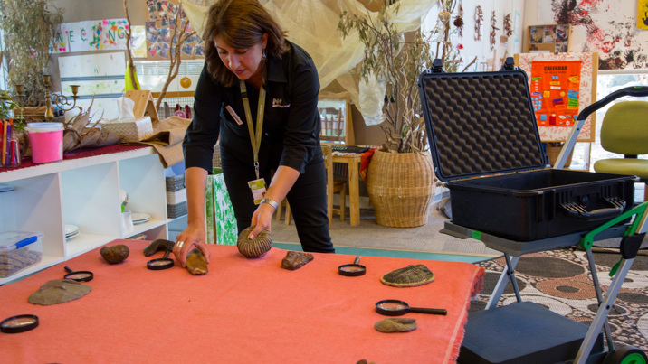 Outreach Program Presenter,  setting up fossils and magnifying glasses on a table at Child Care Centre.
