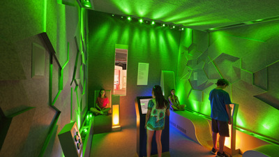 Children using interactives in a room with wall bathed in green light