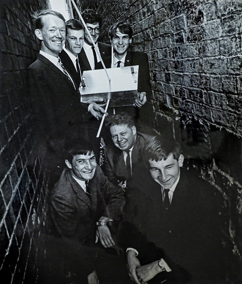 A group of young men in an alleyway holding a satellite. 