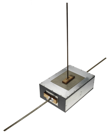 A rectangular, aliminium box with protruding measuring tape. 