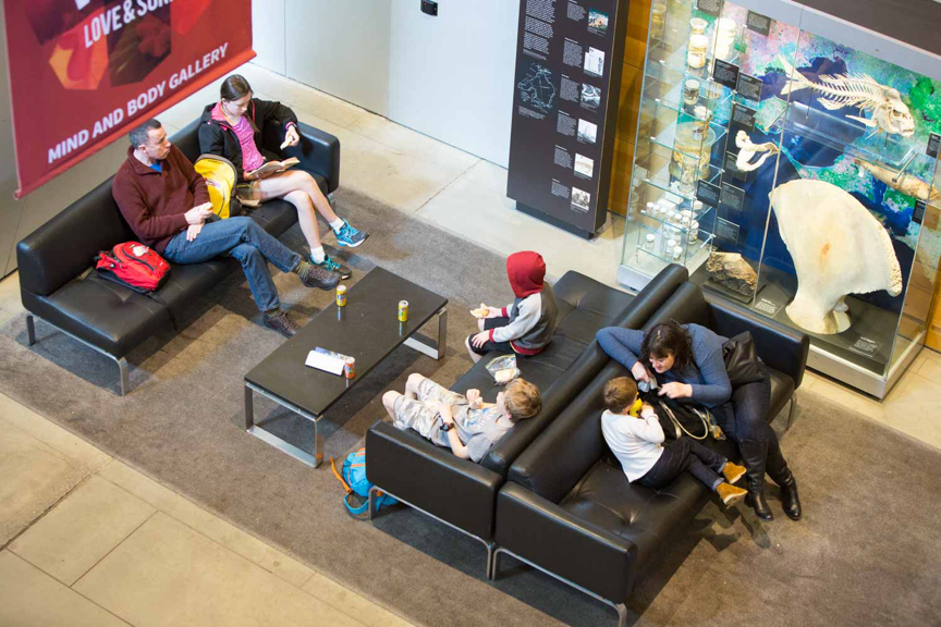 People sitting on couches at the museum, eating their lunch