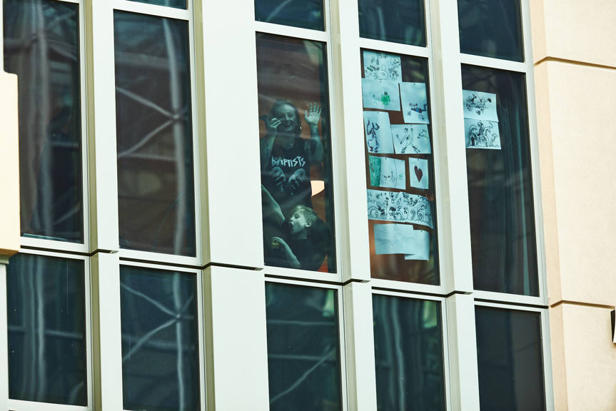 People looking through a window pinned with drawings