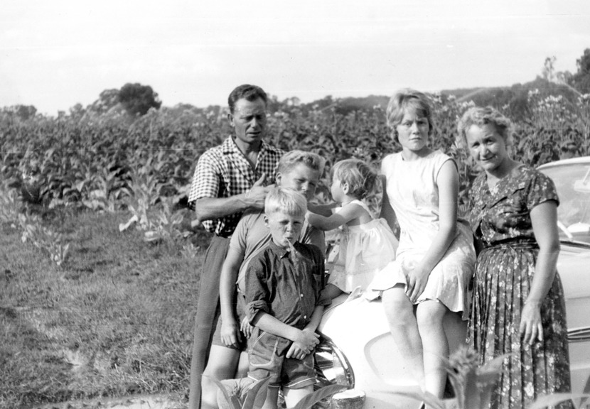 A black and white photo of a family in a field. 