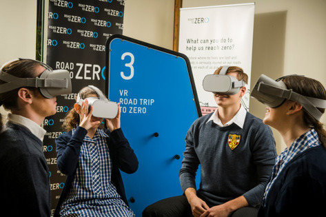 Four students wearing goggles with Road to Zero signage behind them