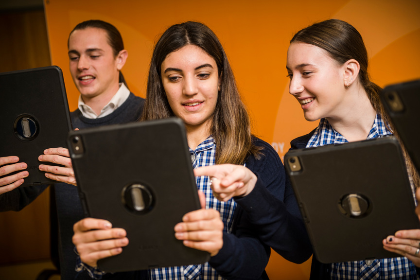 Three students clutching iPads