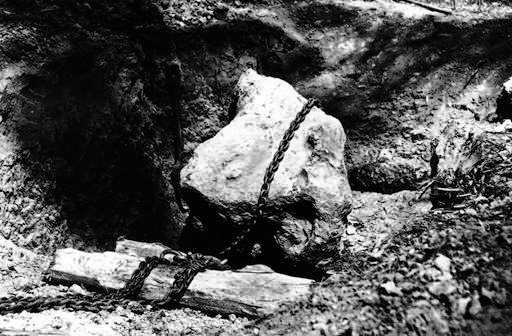 A black and white photograph of a meteorite being excavauted. 