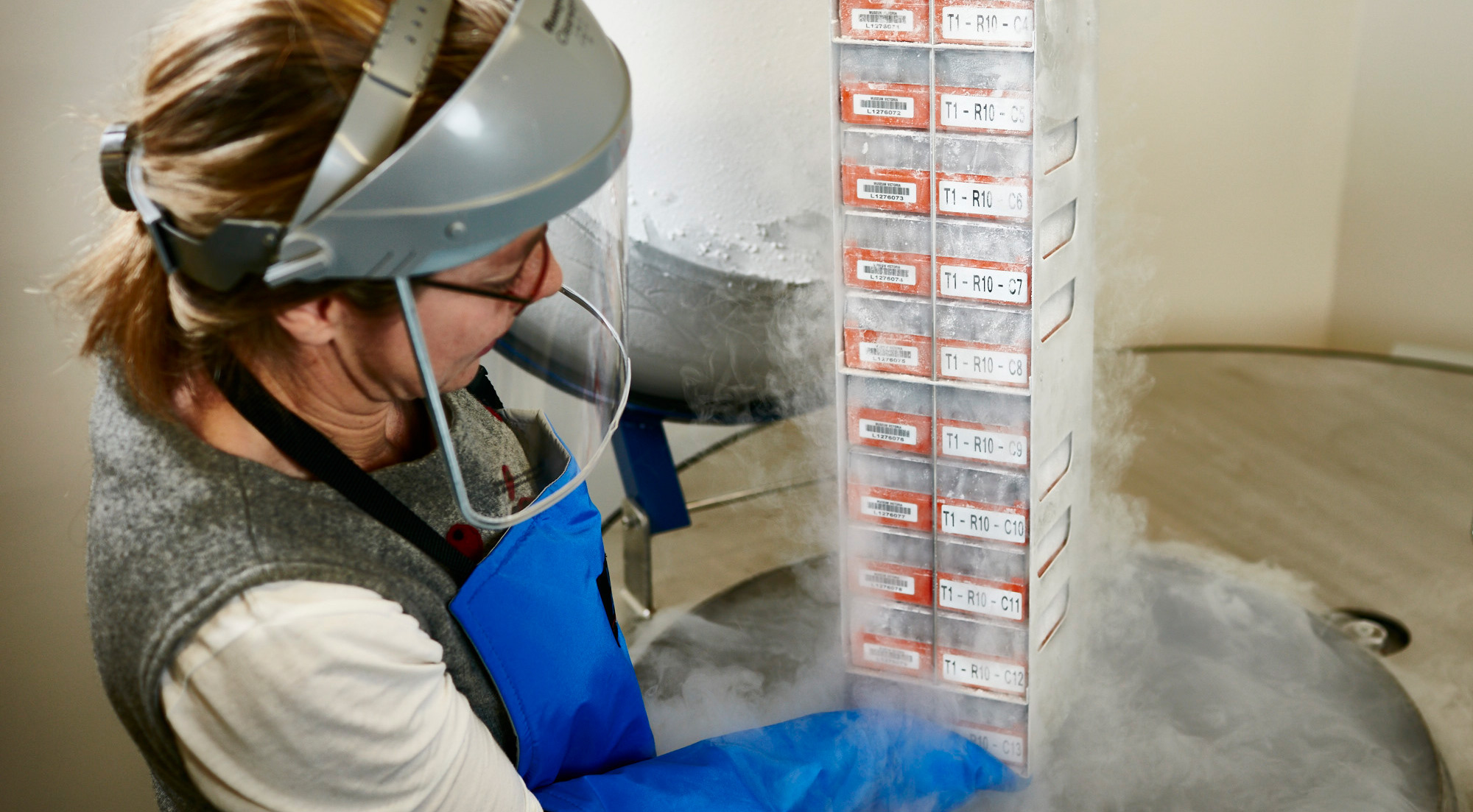 Woman lifting tissues samples from a refrigeration barrel