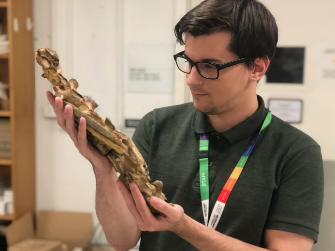 A young man holds a fossil.