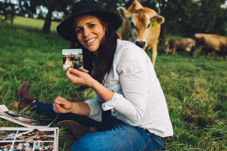 A farmer in the grass looking at old pictures. 