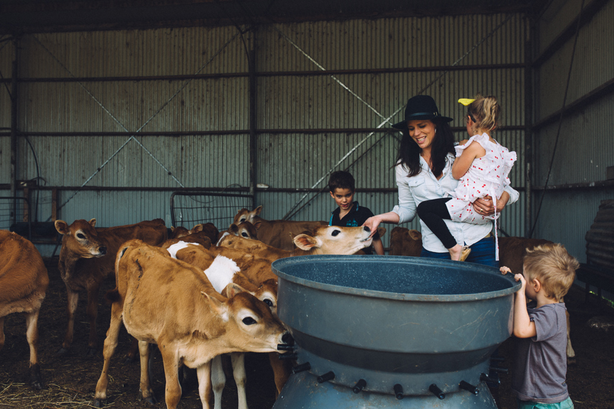 A farmer and her children in a milking shed.