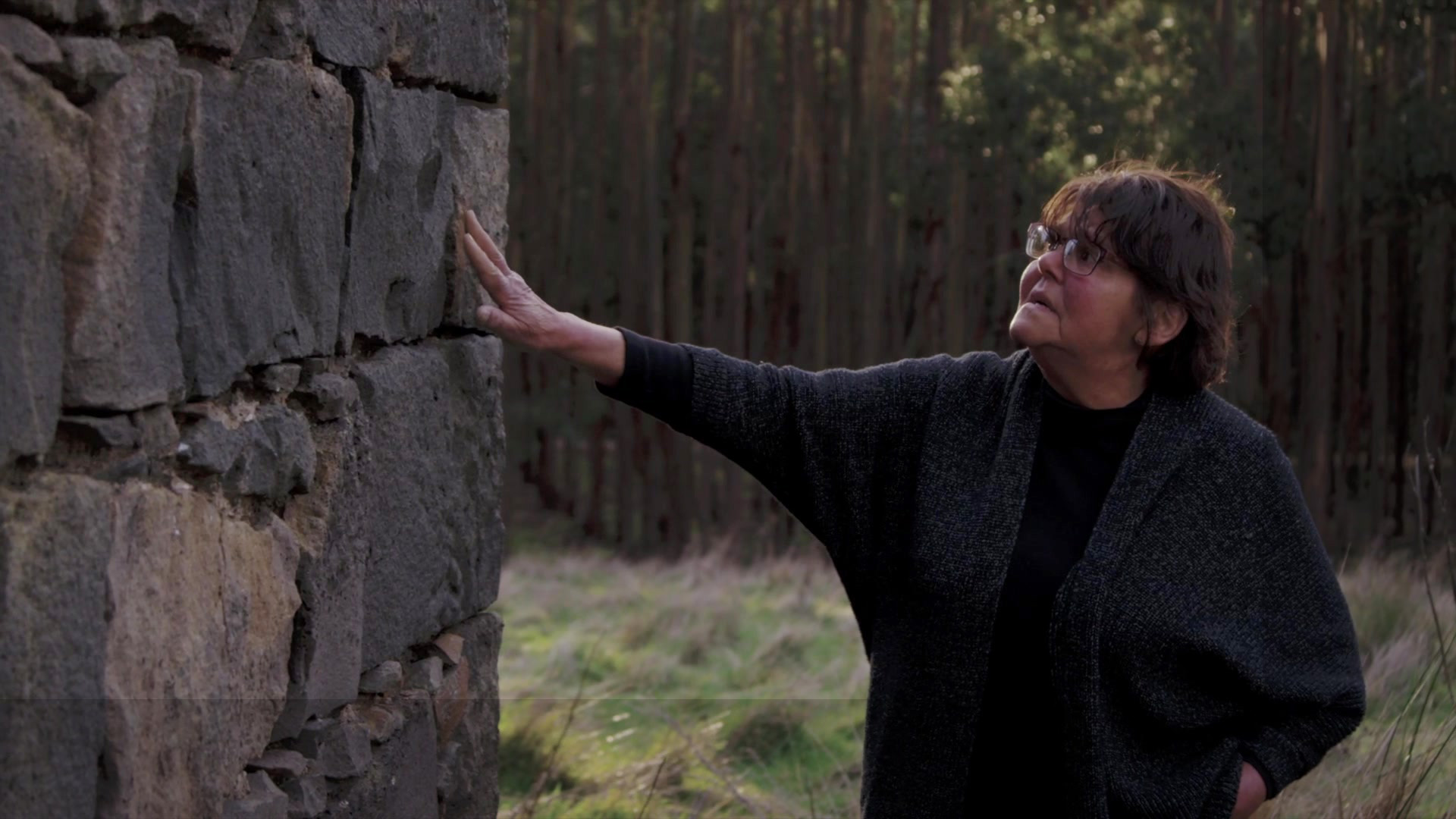 Woman reaching out and touching a bluestone wall