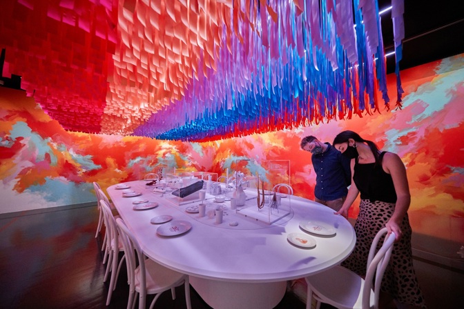 Two people wearing facemasks looking at an exhibition display