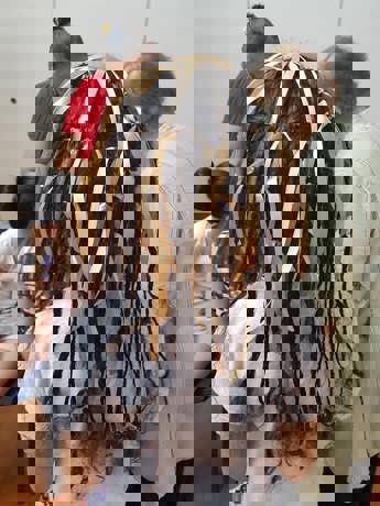 Back of a child's head. Their hair has been braid with ribbons.