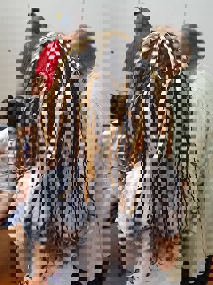 Back of a child's head. Their hair has been braid with ribbons.