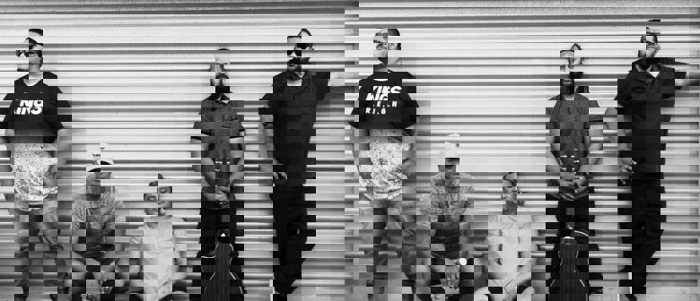 Black and white photo of a group of men one is holding a guitar