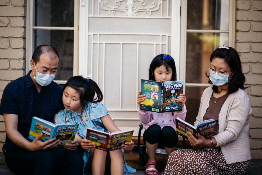 Family sitting on the front porch reading