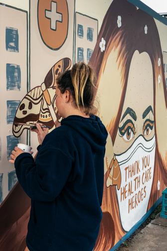 Artist painting a mural on a fence
