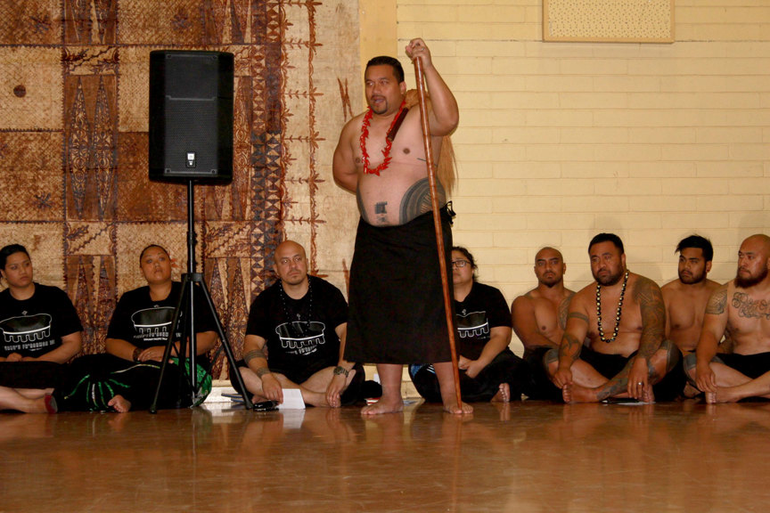 Man standing addressing a group of people sitting on the floor