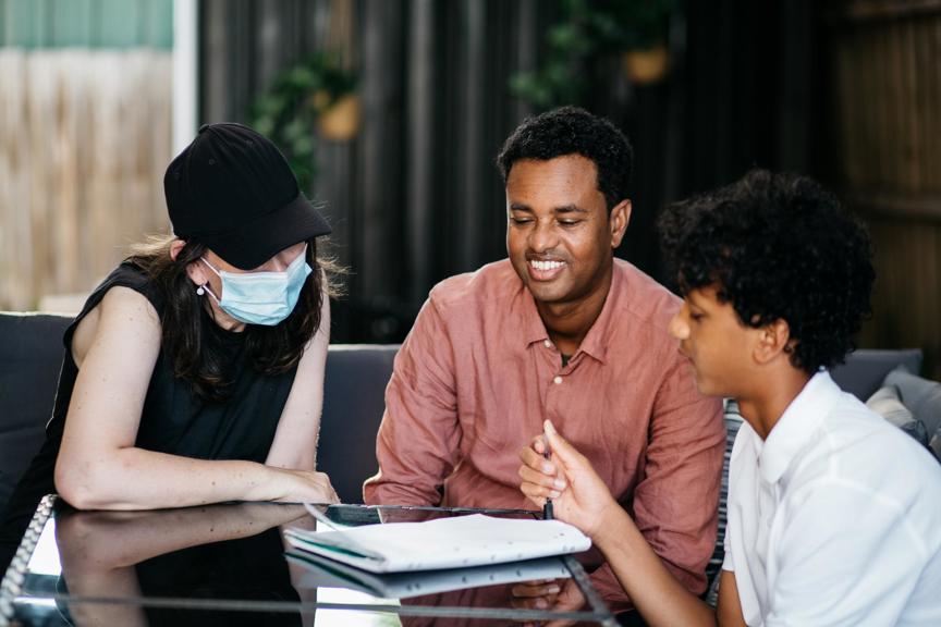 Woman, man & boy reading a journal