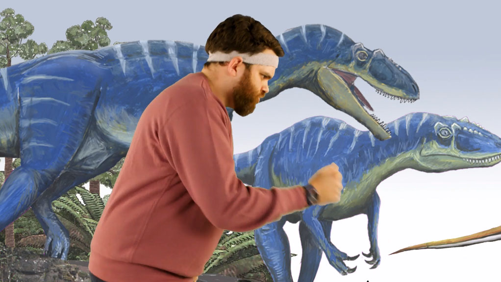 Man posing like a dinosaur in front of a dinosaur mural