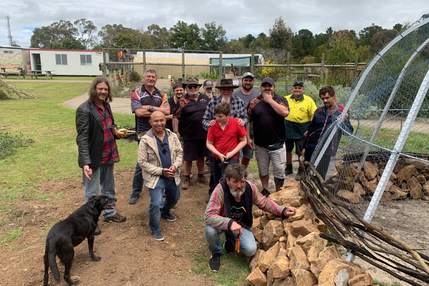 Group of men, a boy and dog posing for a photograph in an outdoor area