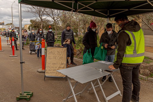People wait in a queue to attend a farmers market