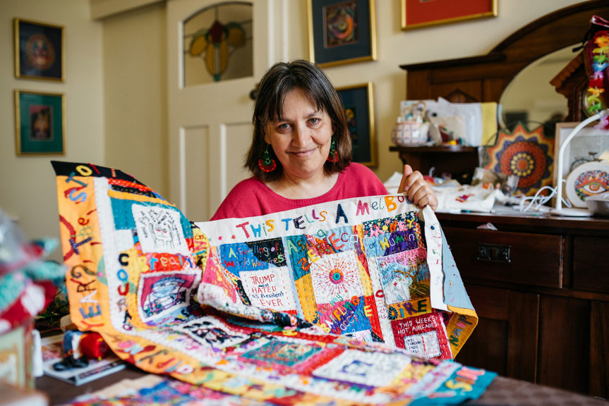 Woman posing holding an embroidered quilt
