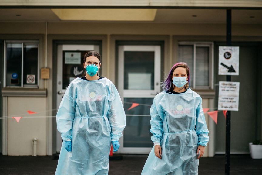 Two woman standing in front of a building wear PPE garmets