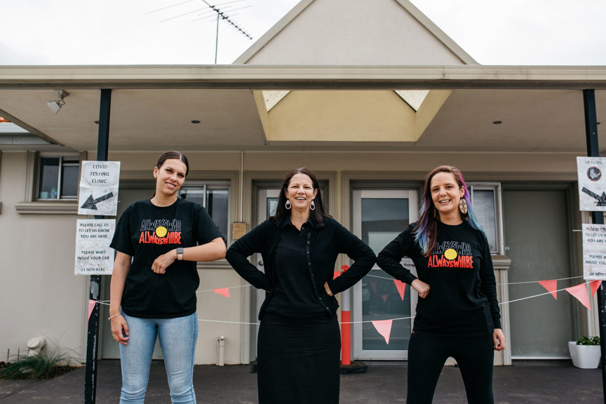 Three woman standing side by side bumping elbows