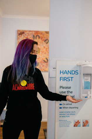 Woman using a wall hand sanitising station