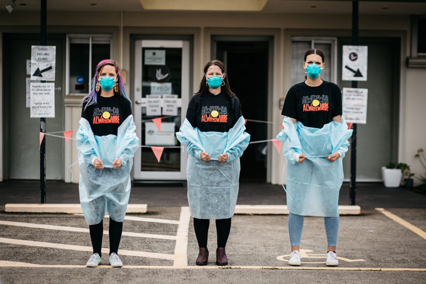 Three woman standing side by side wearing black "Always was always will be" t-shirts and ppe garments