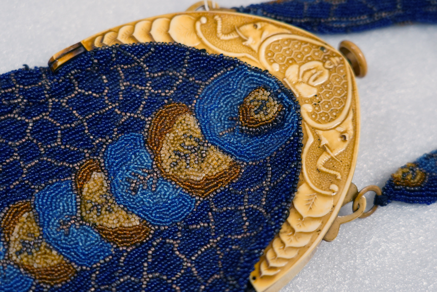 an elaborate blue beaded bag with a fake ivory band on top