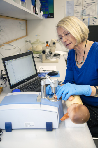 a woman holds a plastic doll to a scanner