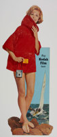 Poster featuring a woman wearing a red garment standing on rocks with an image of sailing boat behind her. Text "Buy Kodak film here"