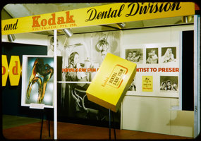 Trade show stand with yellow signage and black and white posters.