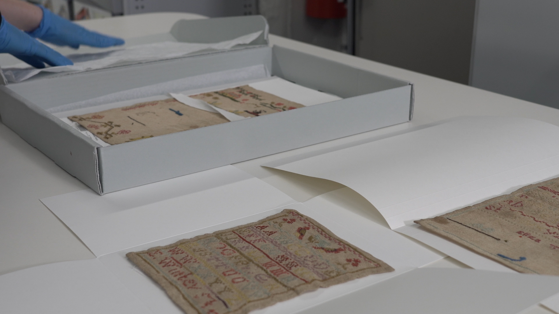 Small sewing samplers layered out on archival tissue paper. 