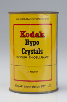 Round tine with painted yellow with black and red decorations and text