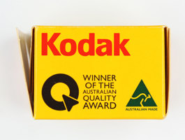 Side of an empty yellow cardboard box; opened; printed in black, gold and red colour scheme.