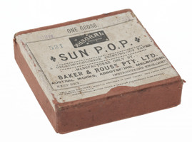 Cardboard box with red paper covering and a white paper label on the top lid printed in black text.