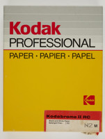 Rectangular box with yellow cardboard lid and black cardboard base. A sticker in lower right corner is printed with product details and seals the box.