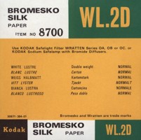 Small square printed label, printed in black, white, green and yellow colour scheme.