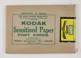 Rectangular brown paper envelope with green printed text and a yellow, black and green sticker label torn open at one end.