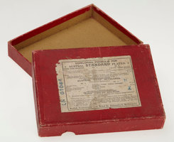 Red box with the lid open to reveal the empty box. Has white paper label with black print on the front.