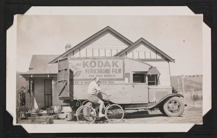 Man riding a bike past a delivery van parked outside a house